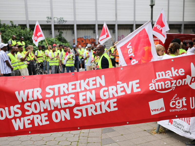 Beschäftigte von Amazon bei einer Demonstration unter dem Titel «Make Amazon Pay! Für gute und gesunde Arbeit bei Amazon!» vor dem Amazon-Verteilzentrum in Hamburg-Veddel. - Foto: Christian Charisius/dpa