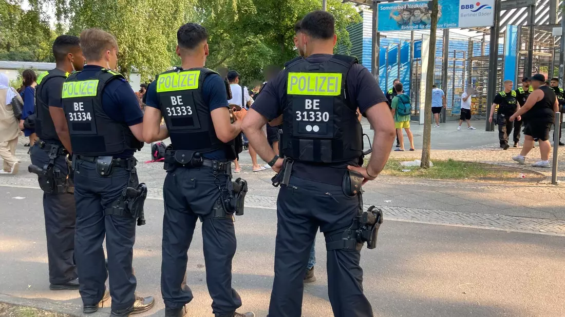 Polizisten stehen vor dem Eingang des Sommerbads in Neukölln. - Bild: Carioline Bock/dpa