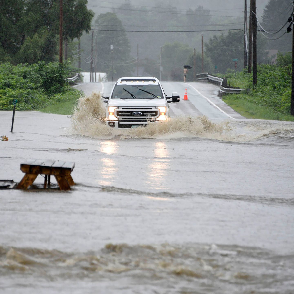 Ein Auto fährt über eine überschwemmte Straße im US-Bundesstaat Vermont. Gouverneur Phil Scott nennt die Situation «historisch und katastrophal». - Foto: Jeb Wallace-Brodeur/The Times Argus/AP/dpa