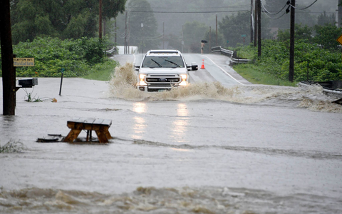 Ein Auto fährt über eine überschwemmte Straße im US-Bundesstaat Vermont. Gouverneur Phil Scott nennt die Situation «historisch und katastrophal». - Foto: Jeb Wallace-Brodeur/The Times Argus/AP/dpa