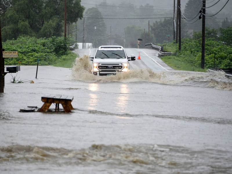 Ein Auto fährt über eine überschwemmte Straße im US-Bundesstaat Vermont. Gouverneur Phil Scott nennt die Situation «historisch und katastrophal». - Foto: Jeb Wallace-Brodeur/The Times Argus/AP/dpa