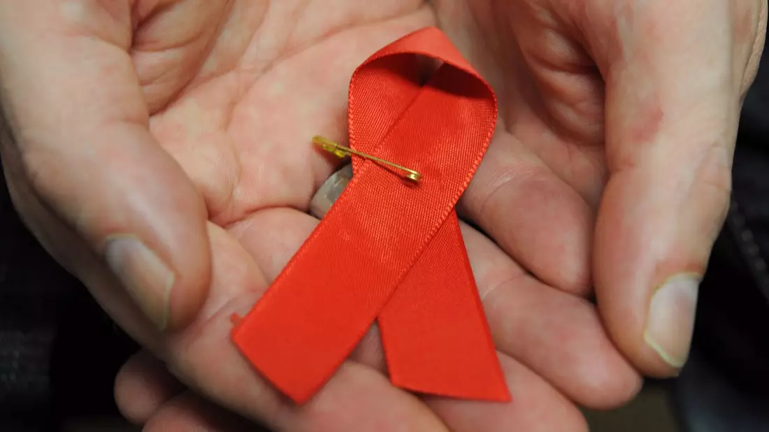 Ein mit dem HI-Virus infizierter Mann mit einer roten Schleife als Symbol der Solidarität mit HIV-Positiven und Aids-Kranken. - Bild: Arne Dedert/dpa