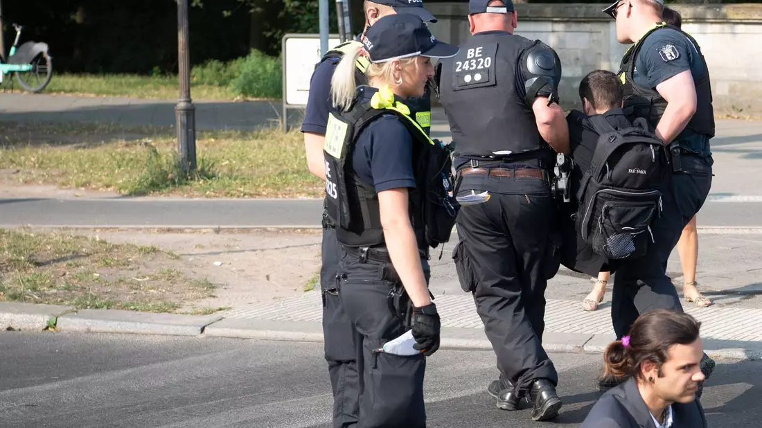 Die Polizei trägt einen Aktivisten der Gruppe Letzte Generation weg, der mit anderen die Fahrbahnen rund um die Siegessäule in Berlin blockiert hat. - Bild: Paul Zinken/dpa