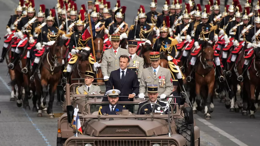 Frankreichs Präsident Emmanuel Macron in einem Kommandowagen mit General Thierry Burkhard, Chef des Generalstabes, bei der Parade auf der Avenue des Champs-Élysées. Frankreich erinnert an den Sturm auf die Bastille im Jahr 1789, der als symbolischer Beginn der Französischen Revolution angesehen wird. - Bild: Christophe Ena/AP