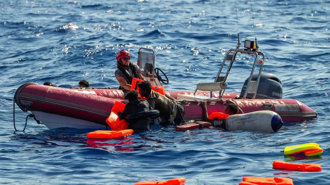 Ein Mitglied der spanischen Nichtregierungsorganisation Open Arms hilft Migranten, an Bord zu kommen. Viele Minderjährige sterben während der Flucht. - Bild: Francisco Seco/AP/dpa