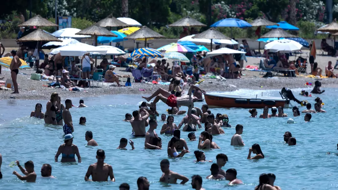 Ein Strandbesucher kühlt sich unter einer Dusche im Vorort Alimos in Athen ab. - Bild: Yorgos Karahalis/AP/dpa