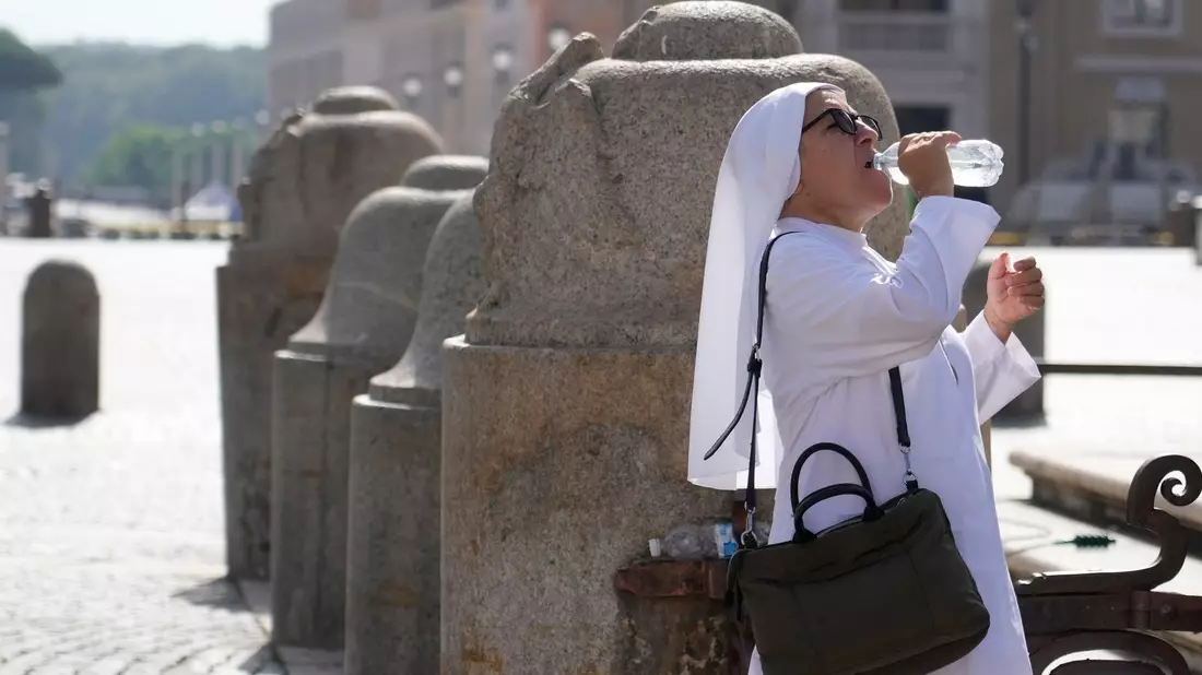 Eine Nonne erfrischt sich auf dem Petersplatz mit einem Schluck aus der Wasserflasche. - Bild: Gregorio Borgia/AP/dpa