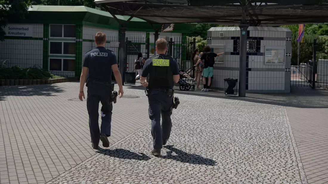 Zwei Polizsten der Mobilen Wache gehen auf das Prinzenbad in Kreuzberg zu. - Bild: Paul Zinken/dpa