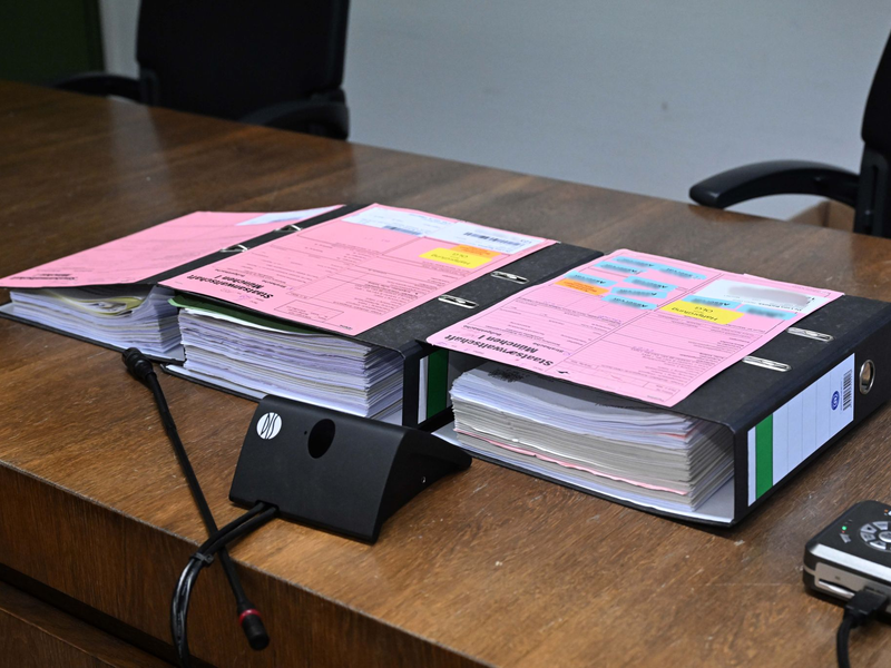 Akten liegen beim Auftakt im Prozess zu einem Mord in einer psychiatrischen Klinik im Sitzungssaal im Landgericht München I. - Foto: Felix Hörhager/dpa