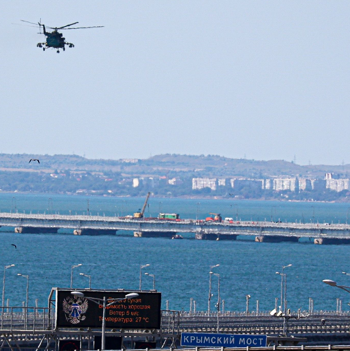 Ein russischer Militärhubschrauber überfliegt die beschädigten Teile der Automobilverbindung der Krim-Brücke. - Foto: -/AP/dpa