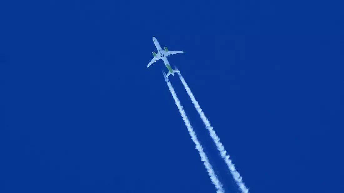 Ein Flugzeug zieht am Himmel einen Kondensstreifen hinter sich her. - Bild: Soeren Stache/dpa