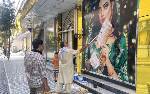 Ein Mitarbeiter eines Schönheitssalons übermalt nach der Machtübernahme der Taliban das Bild einer Frau in Kabul (Archivbild). Frauen haben in der afghanischen Hauptstadt gegen die Schließung der Salons protestiert. - Foto: -/Kyodo/dpa
