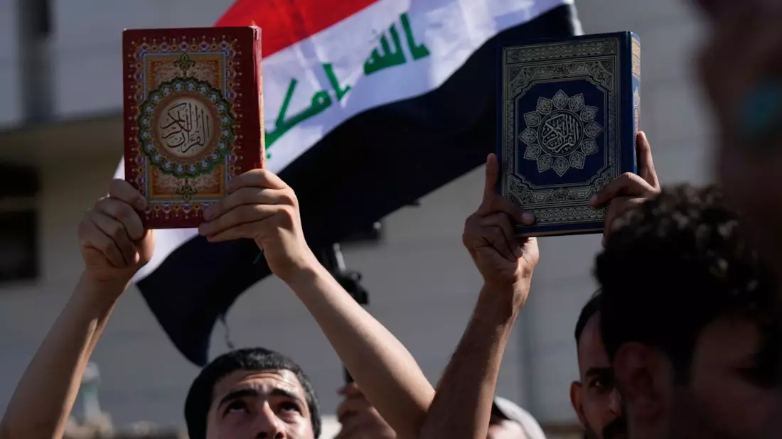 Anhänger des schiitischen Geistlichen Muqtada al-Sadr halten den Koran, das heilige Buch der Muslime, während einer Demonstration vor der schwedischen Botschaft hoch. - Bild: Hadi Mizban/AP