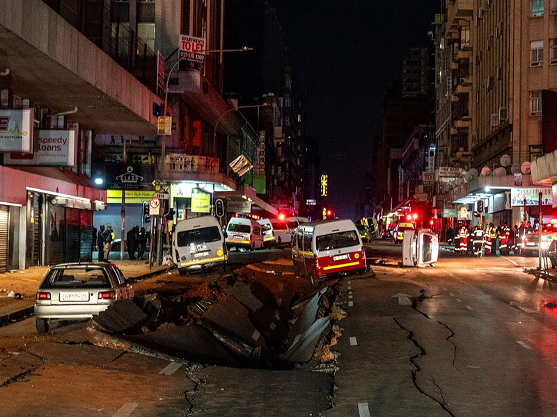 Die mutmaßliche Gasexplosion hat ein Loch in die Straße gerissen. - Foto: Shiraaz Mohamed/AP/dpa