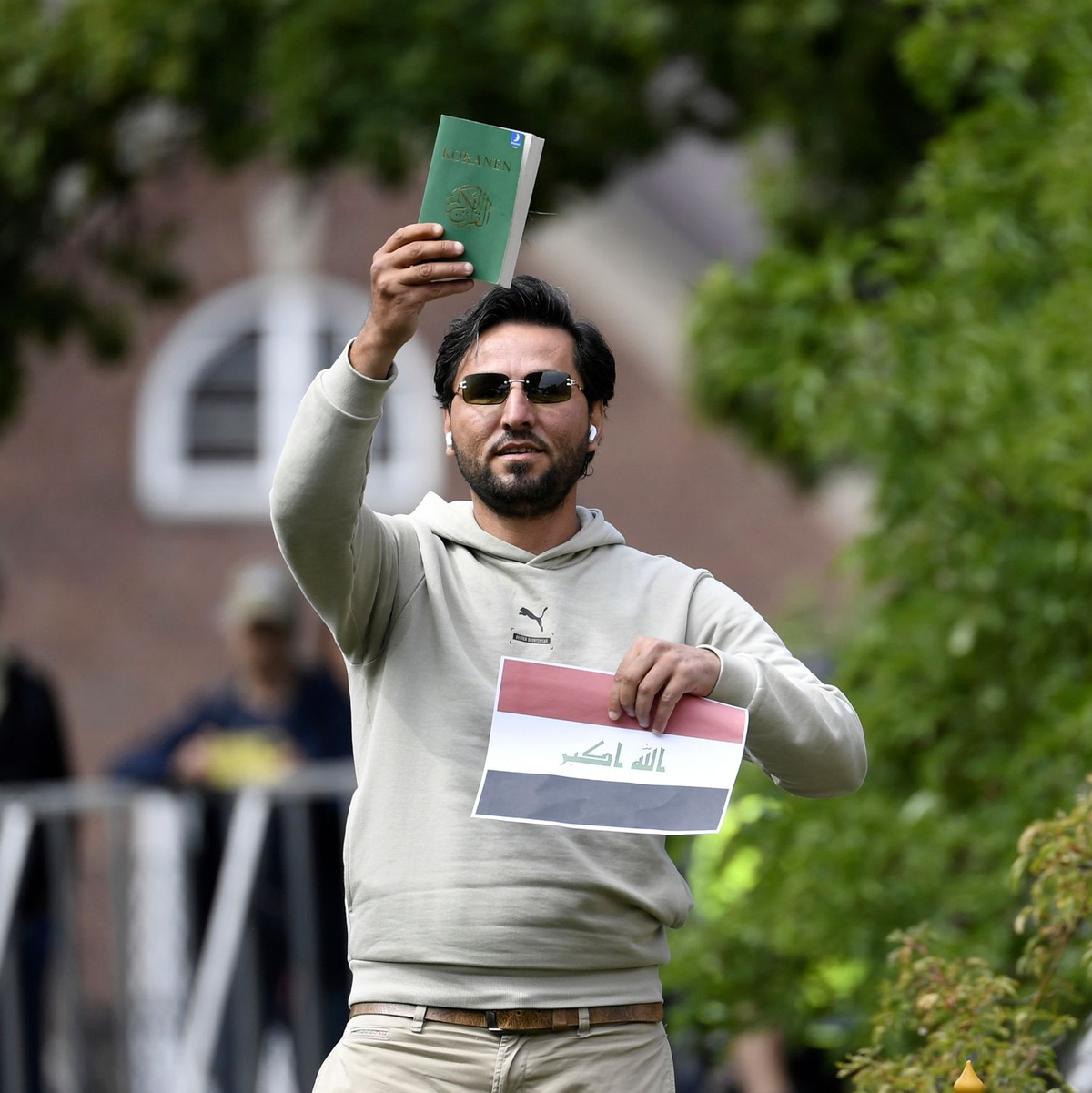 Ein Demonstrant hält eine Kopie des Korans hoch, die er mutmaßlich gemeinsam mit einer irakischen Fahne verbrennen will. - Foto: Oscar Olsson/TT NEWS AGENCY/AP/dpa