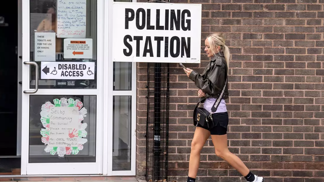 Eine Frau geht an einem Schild des Wahllokals vor dem Selby Community Centre vorbei. - Bild: Danny Lawson/PA/AP/dpa