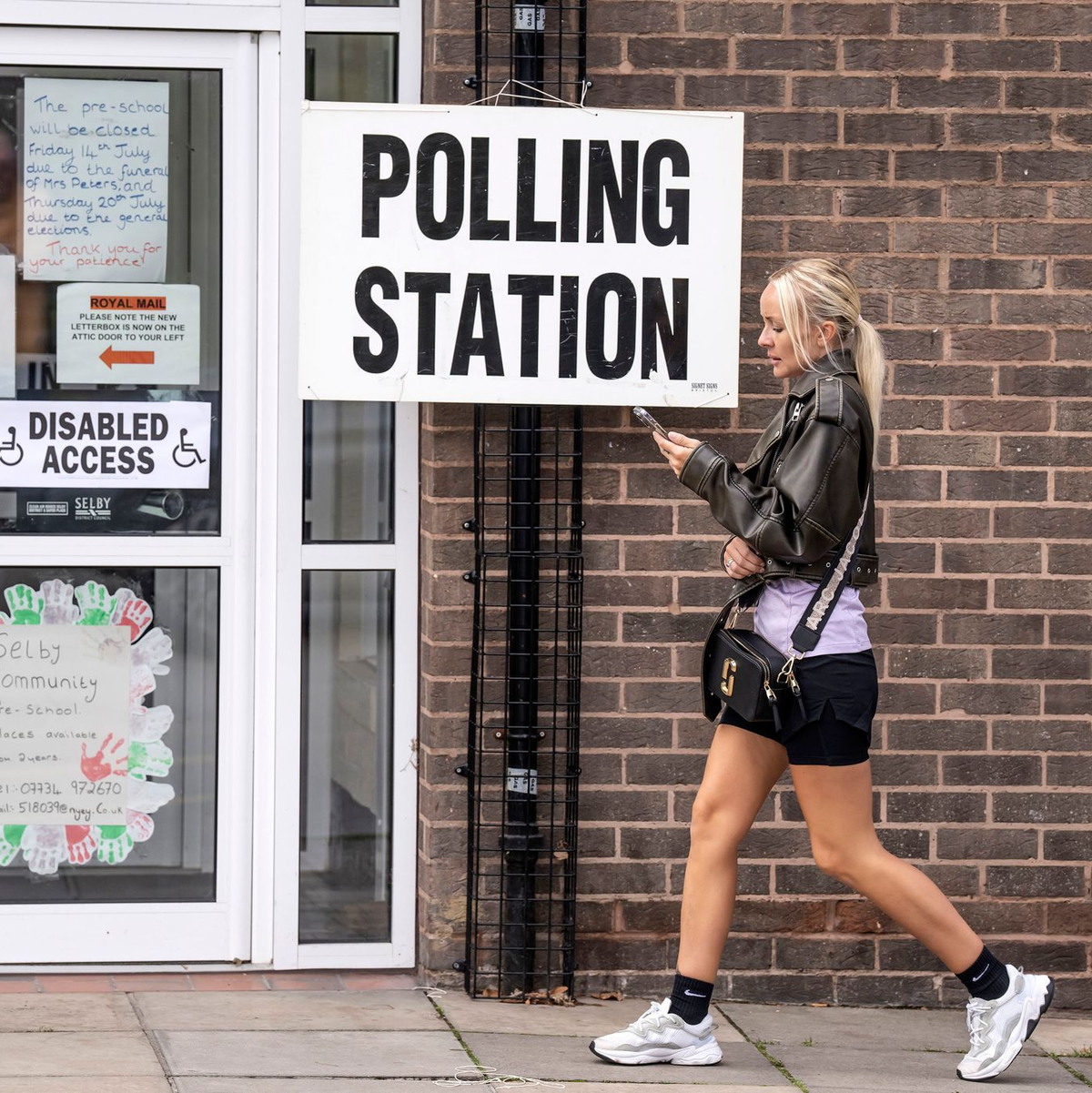 Eine Frau geht an einem Schild des Wahllokals vor dem Selby Community Centre vorbei. - Foto: Danny Lawson/PA/AP/dpa