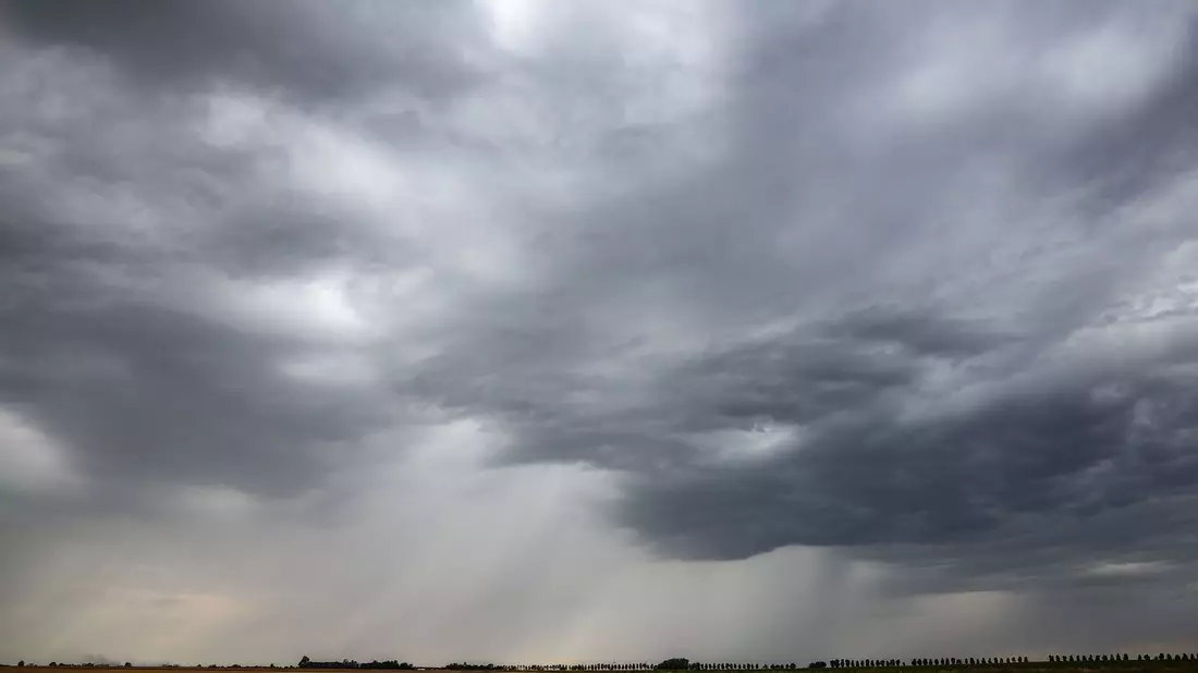Eine Regenfront zieht über ein Getreidefeld hinweg. - Bild: Jan Woitas/dpa
