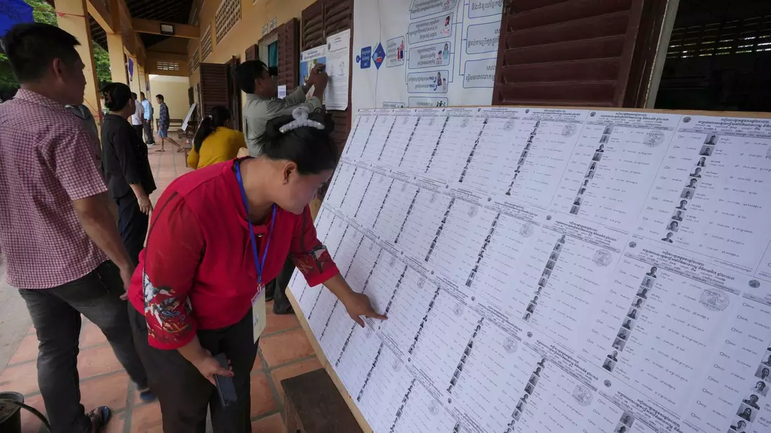 Bewohner von Phnom Penh sehen sich vor der Stimmabgabe in einem Wahllokal eine Registrierungsliste an. - Bild: Heng Sinith/AP