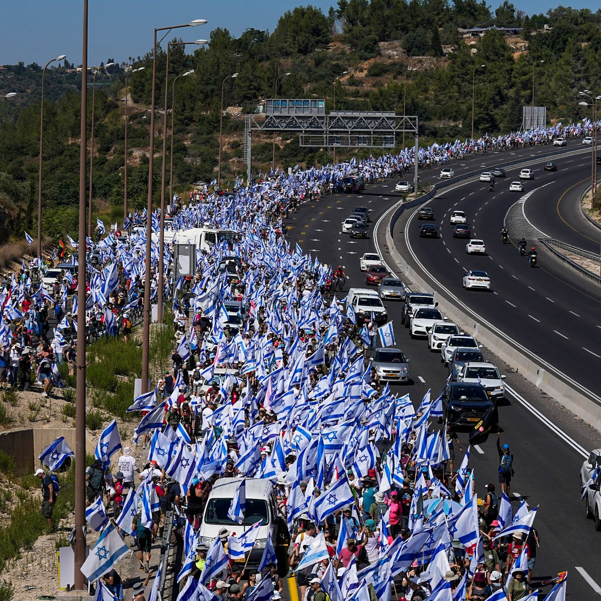 Tausende israelische Demonstranten marschieren entlang einer Autobahn, um gegen die geplante Justizreform der Regierung zu protestieren. - Foto: Ohad Zwigenberg/AP/dpa