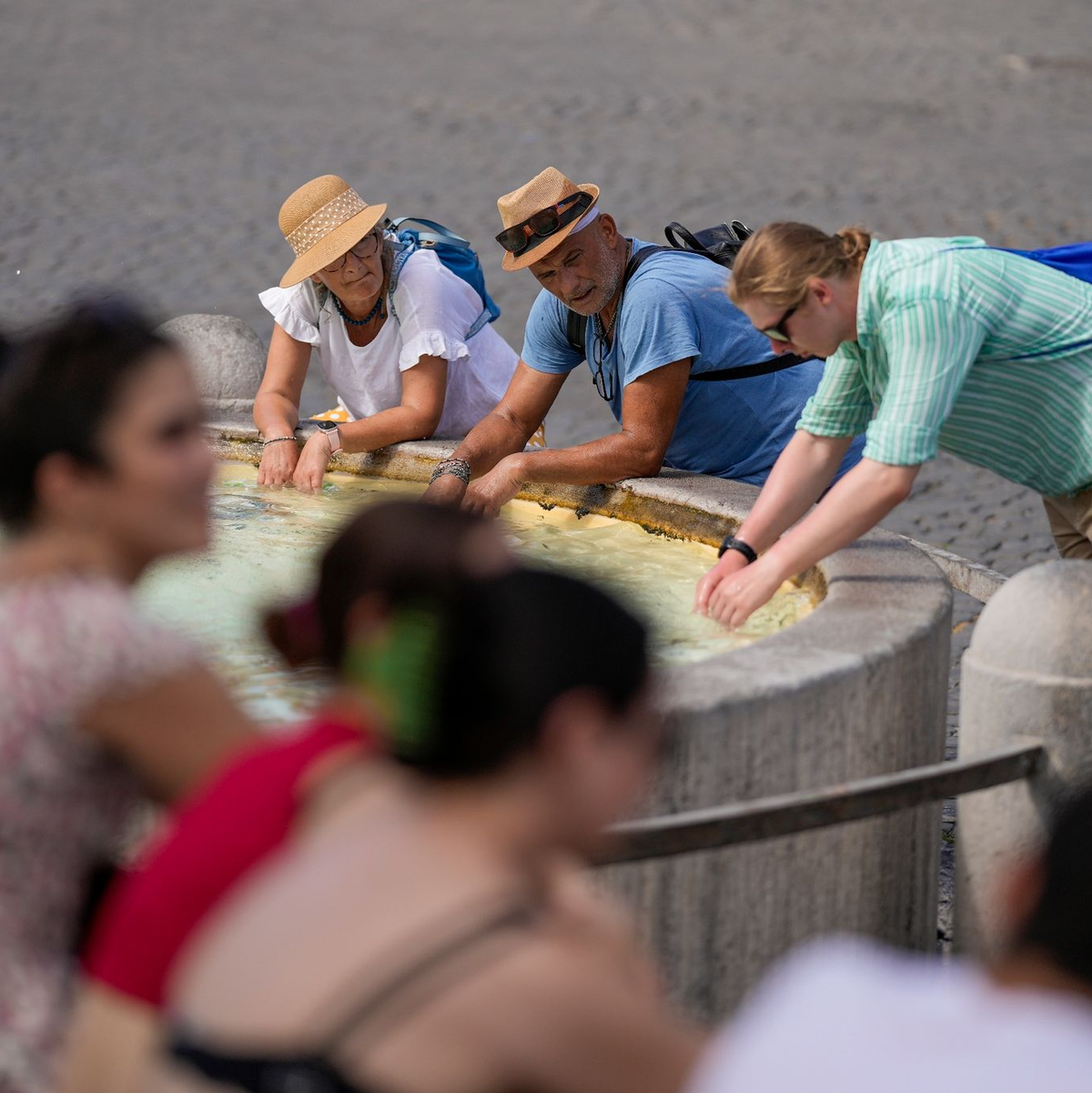 Touristen erfrischen sich bei ihrem Besuch in Rom an einem Brunnen. - Foto: Andrew Medichini/AP