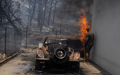 Ein Bewohner versucht, die Flammen im Hof eines Hauses auf der Ägäisinsel zu löschen. - Foto: Petros Giannakouris/AP/dpa