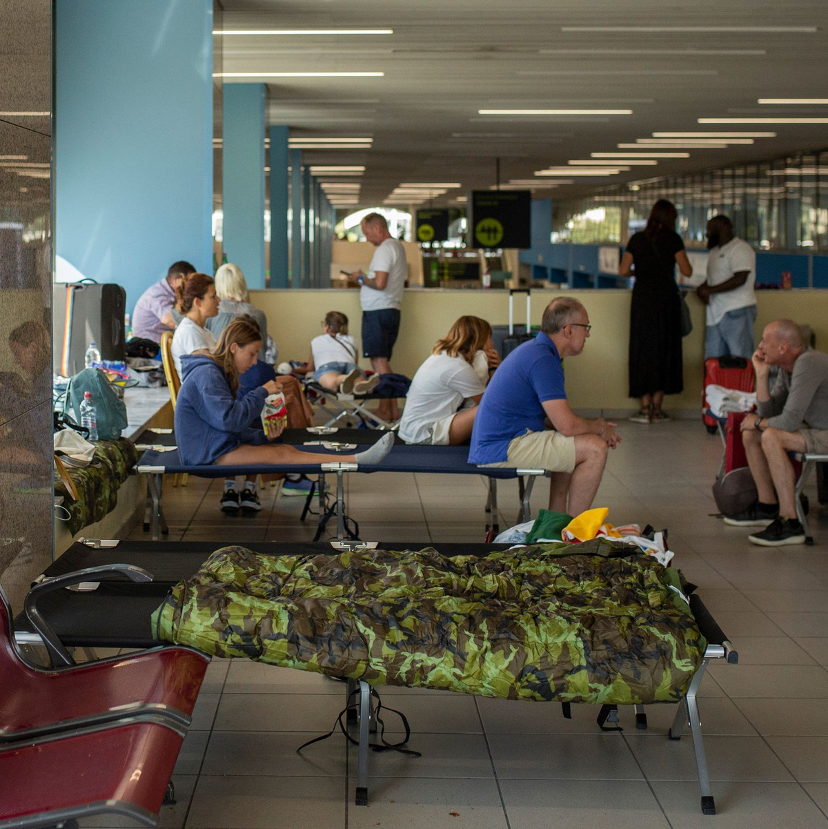 Von den Waldbränden betroffene Touristen warten am internationalen Flughafen Diagoras auf ihren Flug. - Foto: Socrates Baltagiannis/dpa