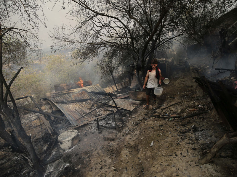 Ein Mann geht an einem Haus vorbei, das bei einem Waldbrand in der algerischen Provinz Bouira niedergebrannt ist. - Foto: XinHua/dpa