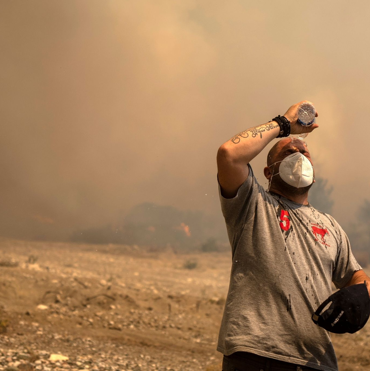 Ein Helfer kühlt sich während eines Waldbrandes in der Ortschaft Vati ab. - Foto: Petros Giannakouris/AP/dpa