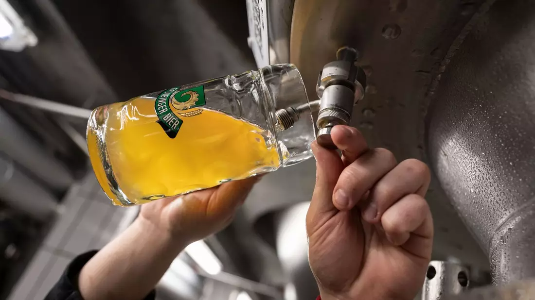 Ein Braumeister entnimmt Bier aus einem Tank. Weltweit wurde 2022 mehr Bier produziert als erwartet. - Bild: Marijan Murat/dpa
