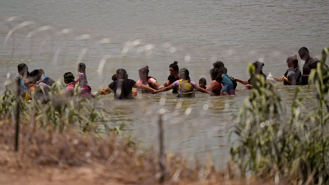Migranten überqueren Hand in Hand den Fluss Rio Grande zwischen Mexiko und den USA. - Bild: Eric Gay/AP