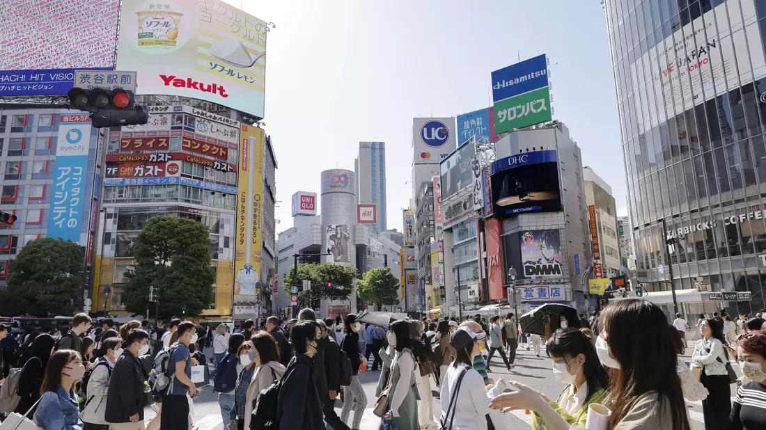 Menschen gehen in Japans Hauptstadt Tokio über eine Kreuzung. - Bild: kyodo/dpa