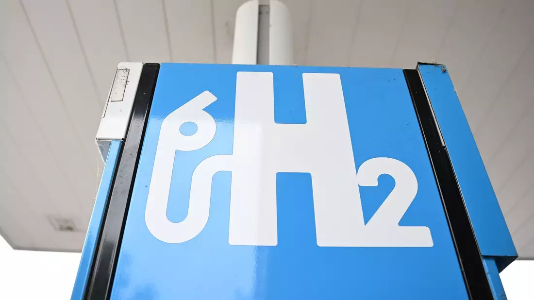 Ein Wasserstoff-Logo an einer Wasserstoff-Tankstelle für Autos. - Bild: Bernd Weißbrod/dpa