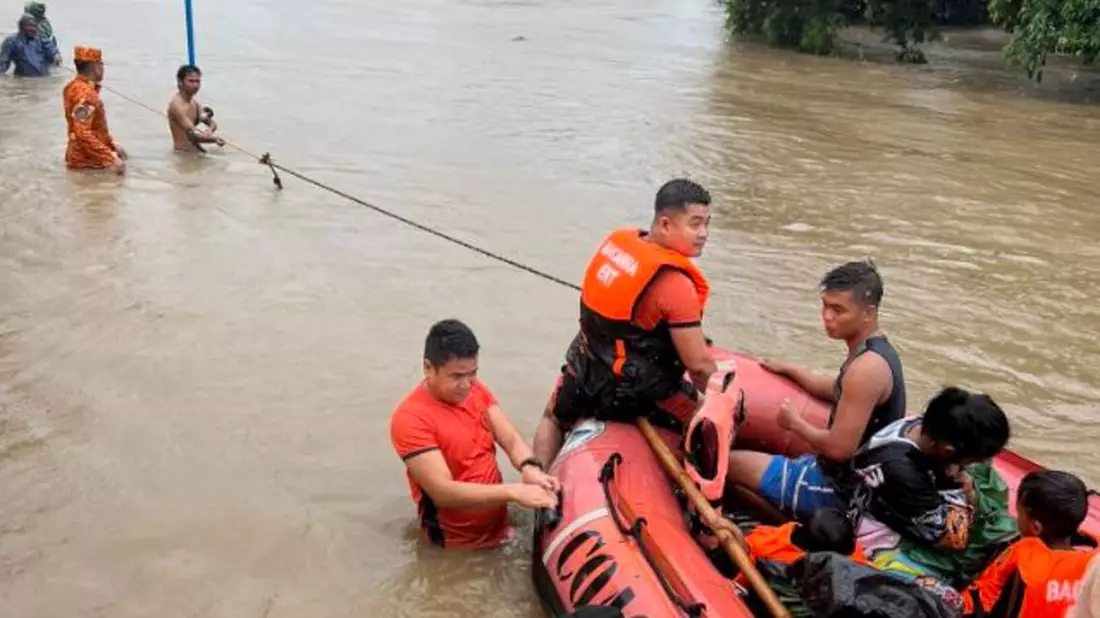 Rettungskräfte verwenden ein Gummiboot, um die Bewohner in höher gelegene Gebiete zu evakuieren. - Bild: Uncredited/Philippine Coast Guard/AP/dpa