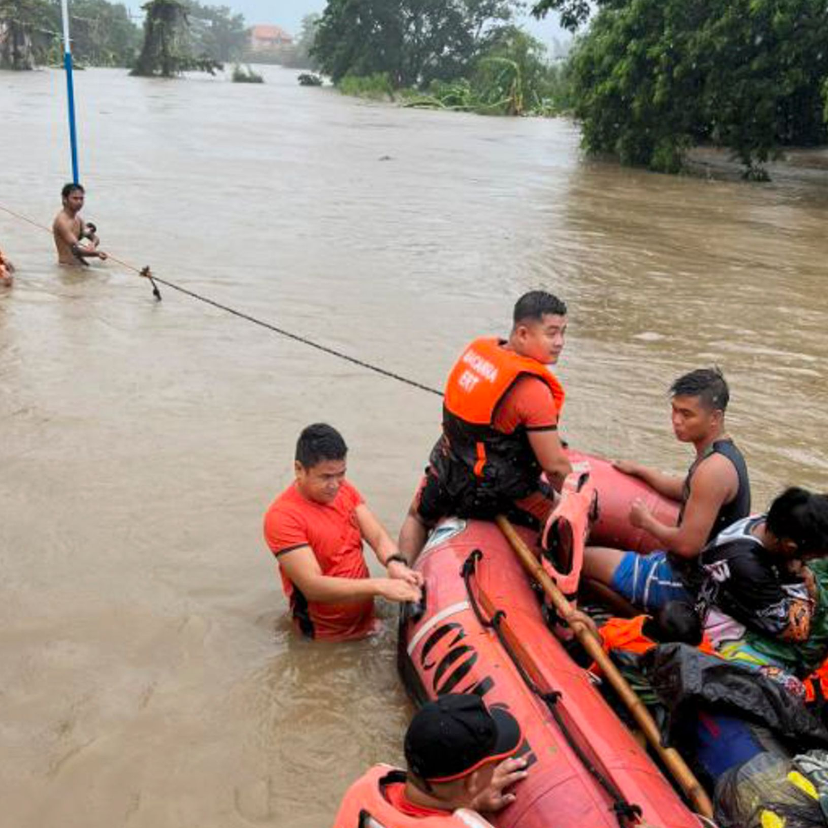 Rettungskräfte verwenden ein Gummiboot, um die Bewohner in höher gelegene Gebiete zu evakuieren. - Foto: Uncredited/Philippine Coast Guard/AP/dpa