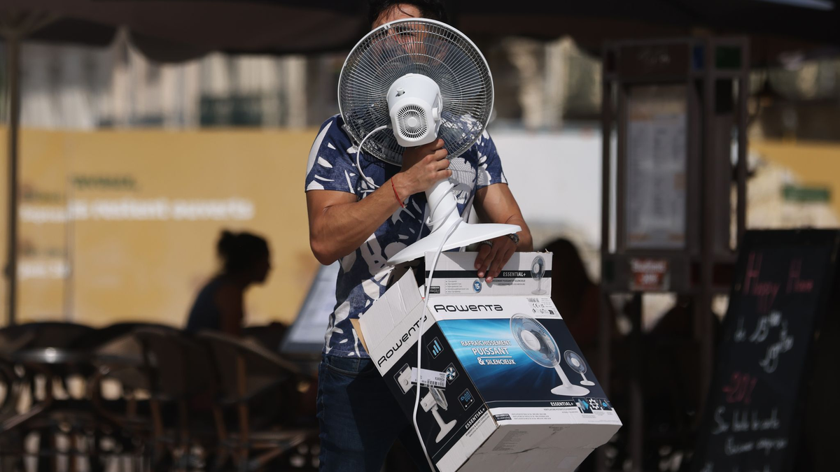 Ein Mann trägt einen Ventilator, während er bei 38 Grad Celsius über die Place de la Comedie in Montpellier geht. - Foto: Gao Jing/XinHua/dpa