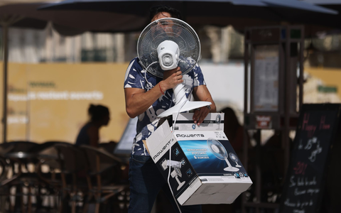Ein Mann trägt einen Ventilator, während er bei 38 Grad Celsius über die Place de la Comedie in Montpellier geht. - Foto: Gao Jing/XinHua/dpa