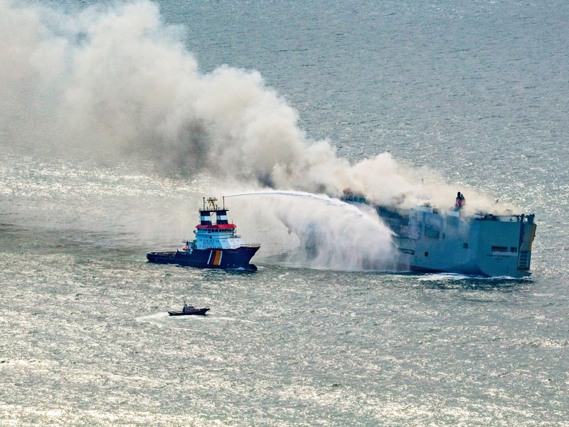 Eine Luftaufnahme zeigt einen deutschen Notschlepper(l), der das Feuer auf dem brennenden Frachter «Fremantle Highway» bekämpft. - Foto: Herman IJsseling/FLYING FOCUS aerial photography/dpa
