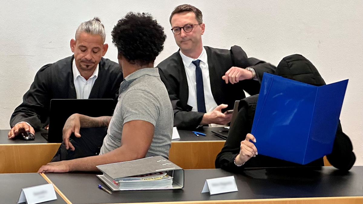 Eine ehemalige Justizvollzugsbeamtin (vorn r) und ein Häftling der Justizvollzugsanstalt Kaisheim (vorn l) sitzen auf der Anklagebank im Strafjustizzentrum Augsburg, im Hintergrund die Strafverteidiger. - Foto: Ulf Vogler/dpa