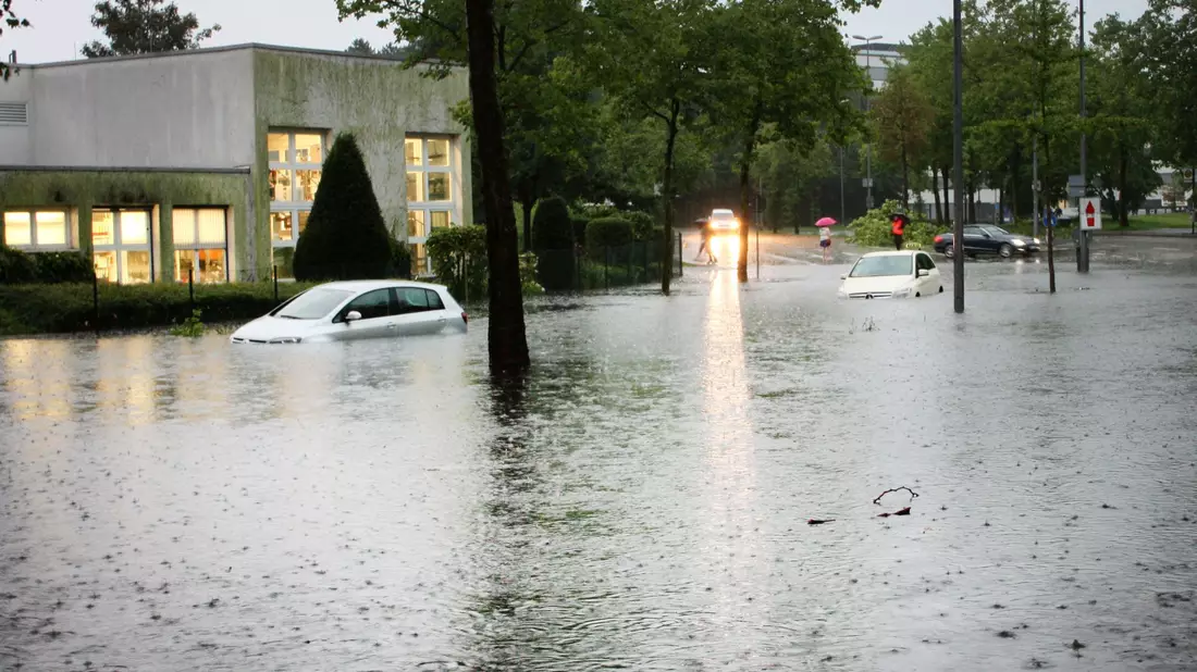 Autos auf einer überfluteten Straße in Münster. Der Grund: Heftige Regenfälle. - Bild: Philipp Seibt/dpa