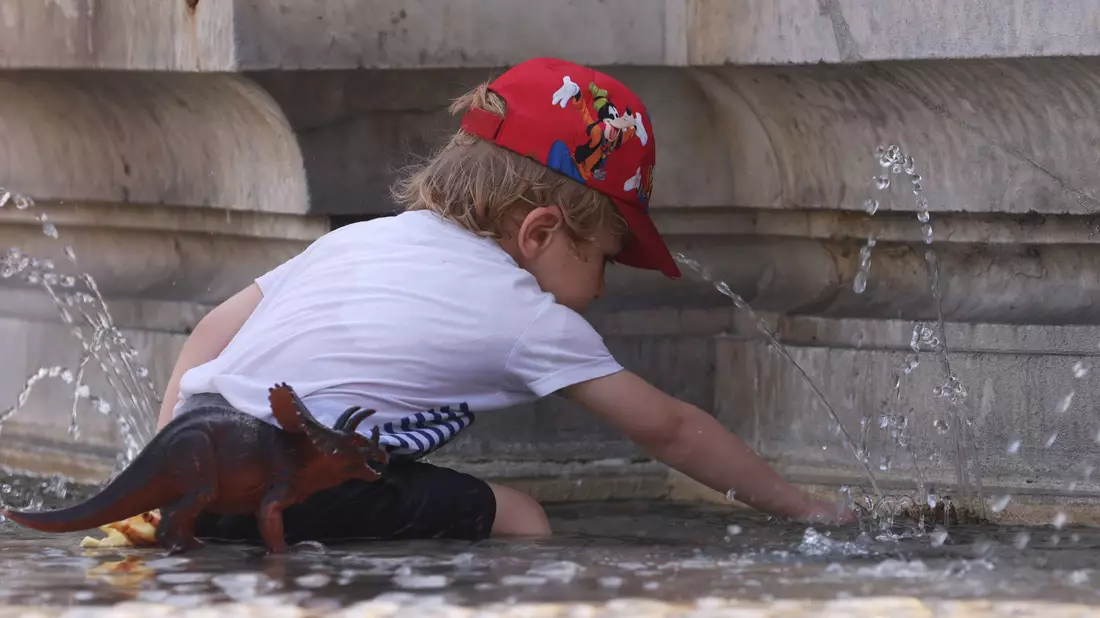 Ein Kind kühlt sich bei 38 Grad Celsius an einem Brunnen ab. - Bild: Gao Jing/XinHua/dpa