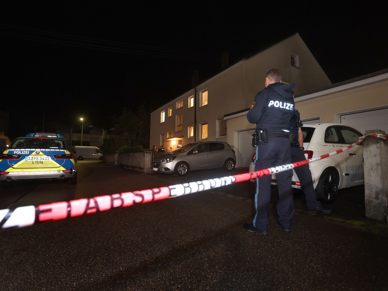 Polizisten am Tatort vor dem Haus in Langweid, in dem drei Menschen erschossen wurden. - Foto: Karl-Josef Hildenbrand/dpa