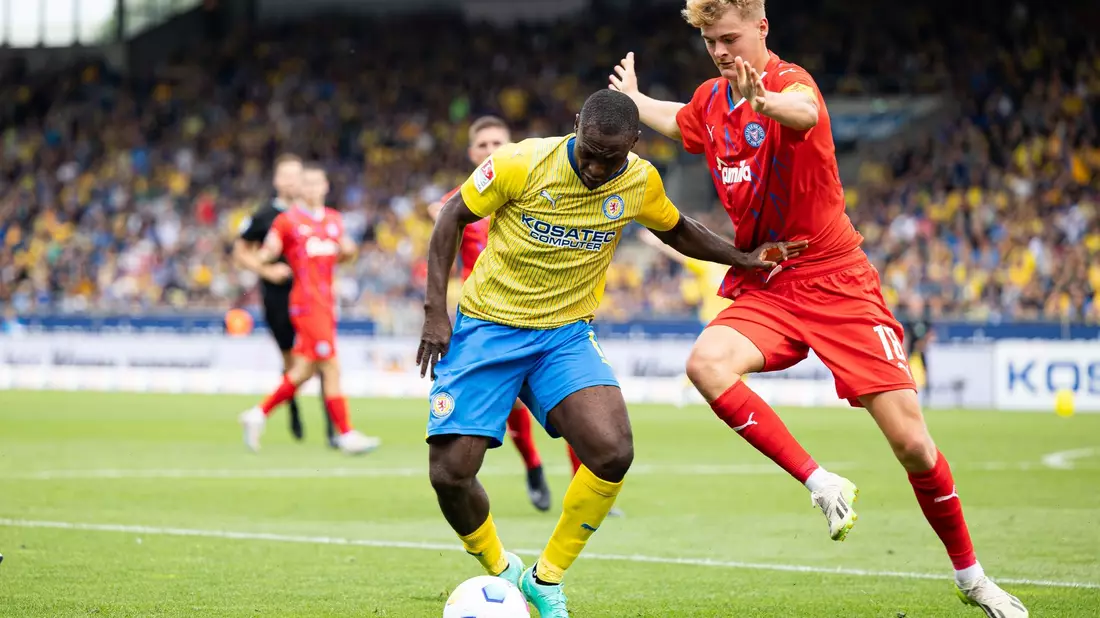 Der Braunschweiger Anthony Ujah (l) im Zweikampf mit dem Kieler Tom Rothe. - Bild: Michael Matthey/dpa
