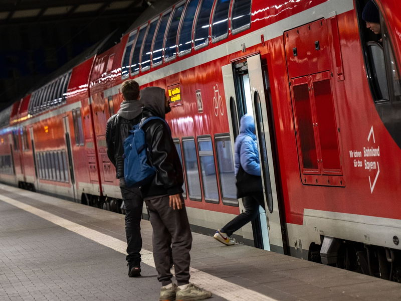 Reisende im Hauptbahnhof München vor einer Regionalbahn. Die Mitglieder der Eisenbahn- und Verkehrsgewerkschaft (EVG) stimmen im August darüber ab, ob es zu einem Tarifabschluss mit der Deutschen Bahn kommt oder zu unbefristeten Streiks. - Foto: Peter Kneffel/dpa
