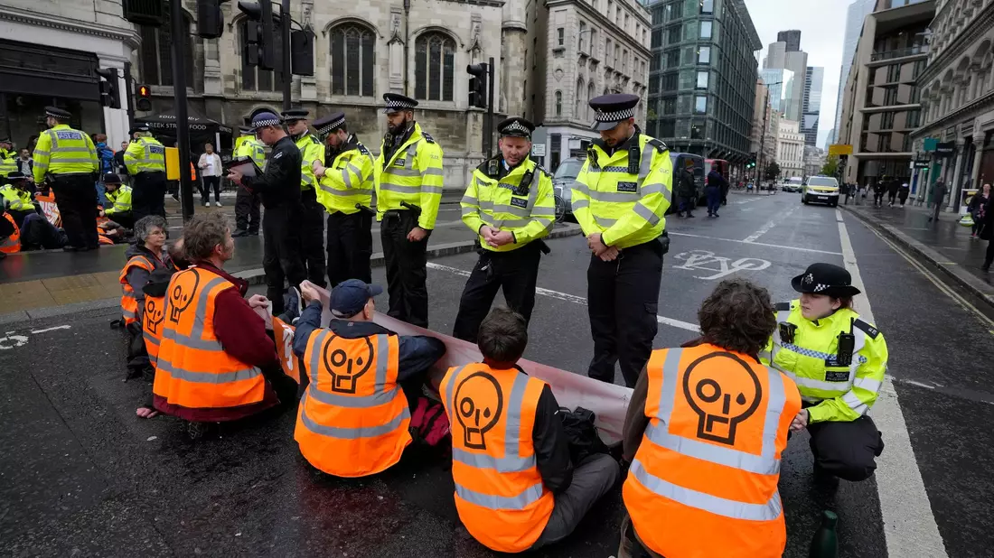 Protestaktion: Aktivisten der Gruppe «Just Stop Oil» blockieren im Herbst 2022 eine Straße in London und fordern, zukünftige Gas- und Ölprojekte zu stoppen. - Bild: Kirsty Wigglesworth/AP/dpa