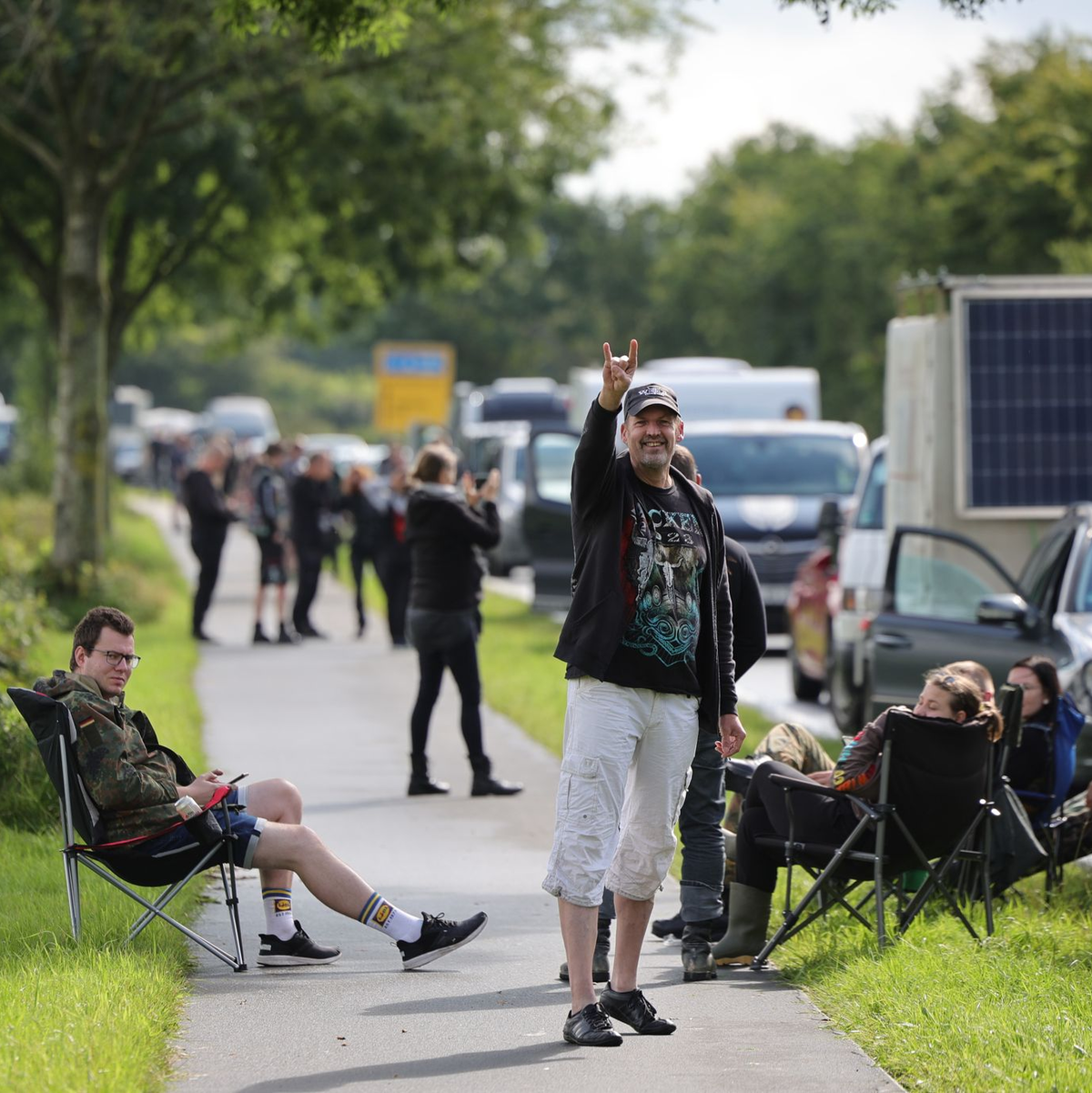 Metal-Fans gehen über das schlammige Festivalgelände. - Foto: Christian Charisius/dpa