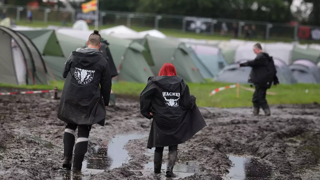 Metal-Fans auf dem schlammigen Festivalgelände in Wacken. - Bild: Christian Charisius/dpa