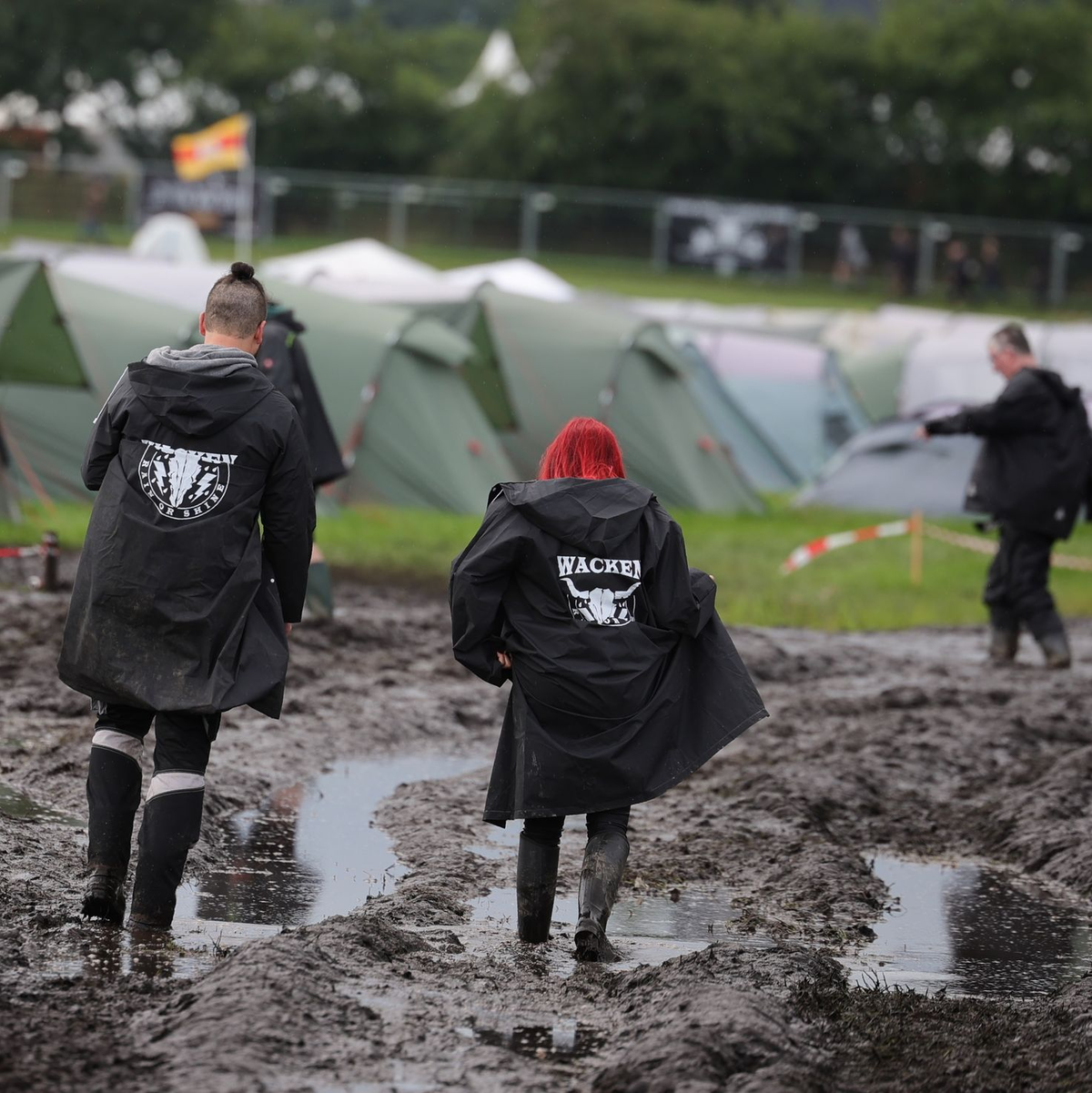 Metal-Fans auf dem schlammigen Festivalgelände in Wacken. - Foto: Christian Charisius/dpa