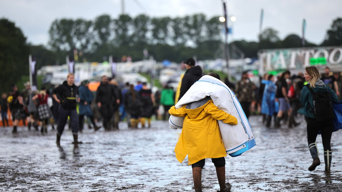Metal-Fans sind auf dem schlammigen Festivalgelände unterwegs. - Foto: Christian Charisius/dpa