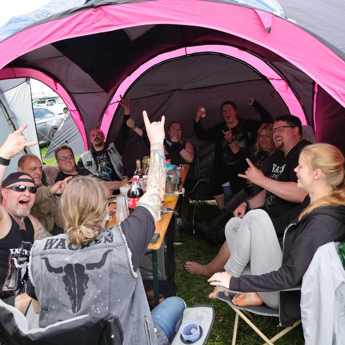 Metal-Fans aus Kiel feiern auf einem Zeltplatz auf dem vom Regen aufgeweichten Festivalgelände. - Foto: Christian Charisius/dpa